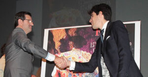 Marsella y López Simón, dándose la mano frente al cartel de la feria.