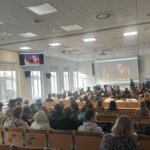 Auditorio lleno de estudiantes durante una presentación en pantalla
