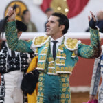 Torero en traje de luces levantando un trofeo tras una faena exitosa.