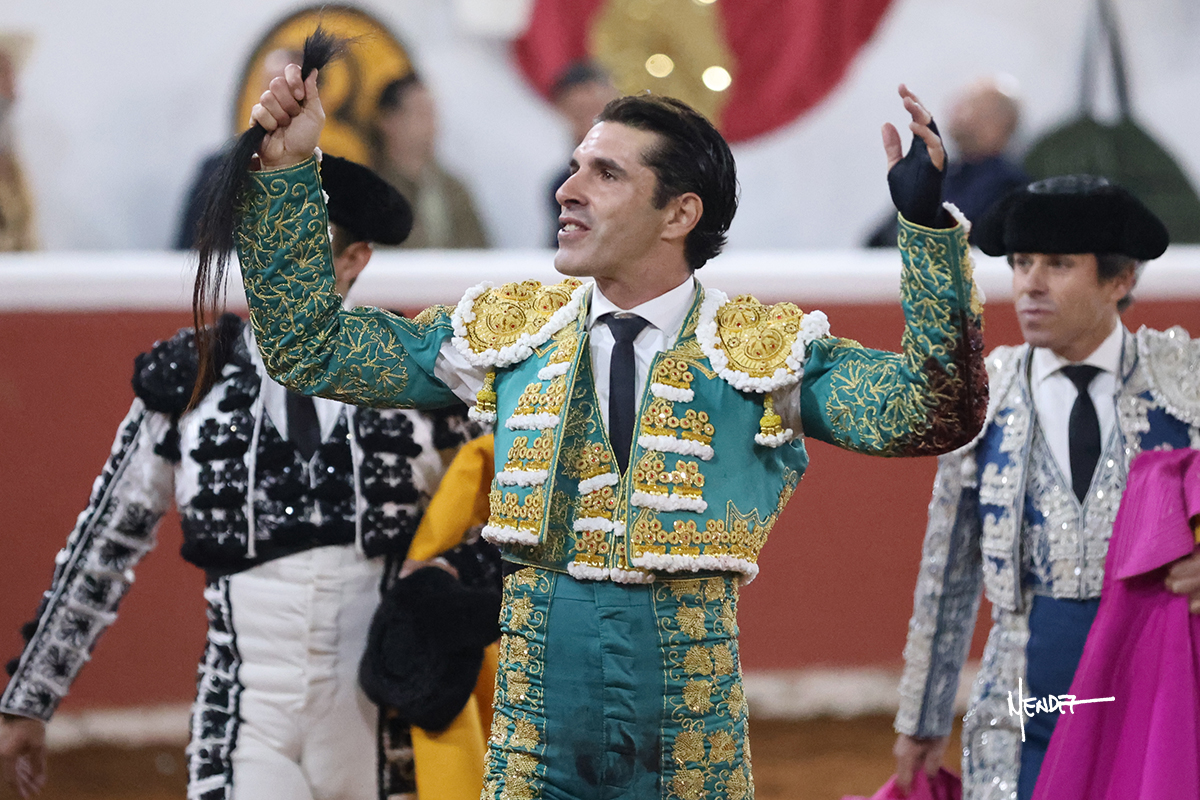 Torero en traje de luces levantando un trofeo tras una faena exitosa.